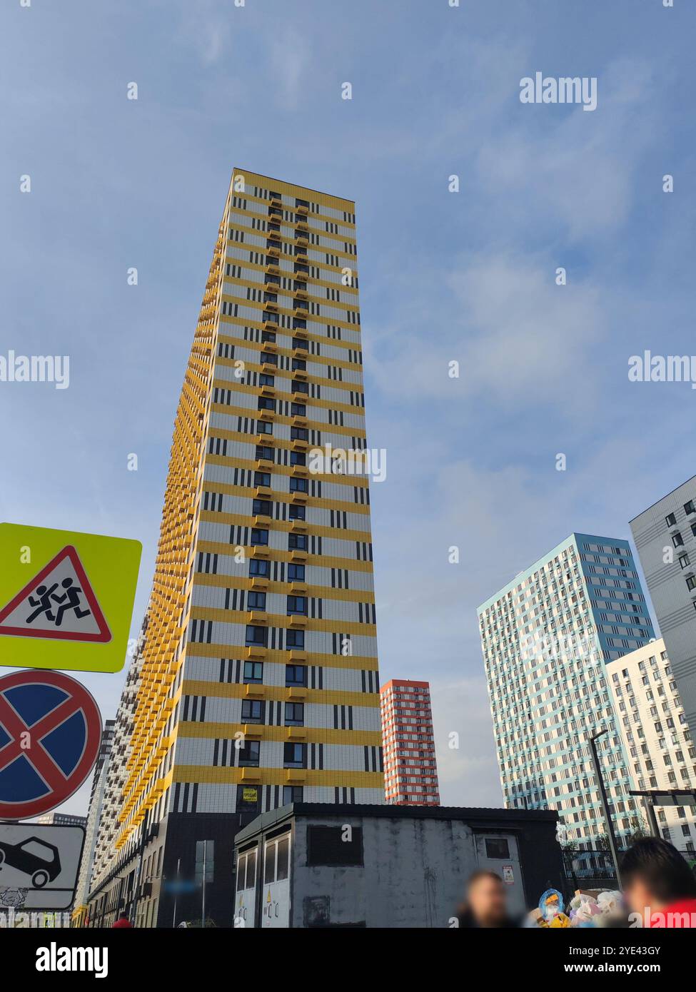 Two high-rise residential buildings, one yellow and white, the other ...