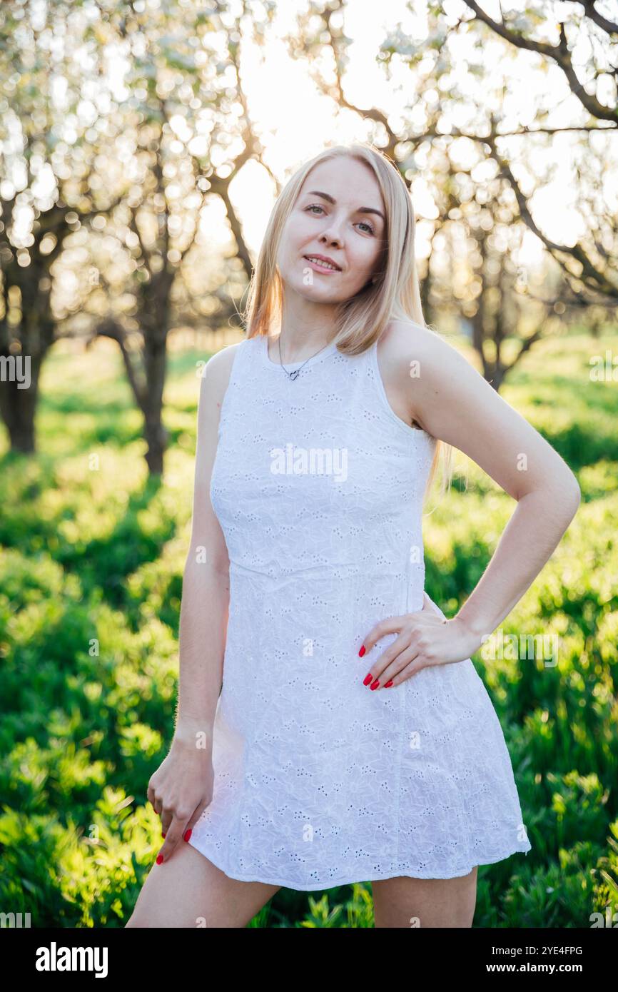 Beautiful woman in summer dress walking in the garden of flowering ...