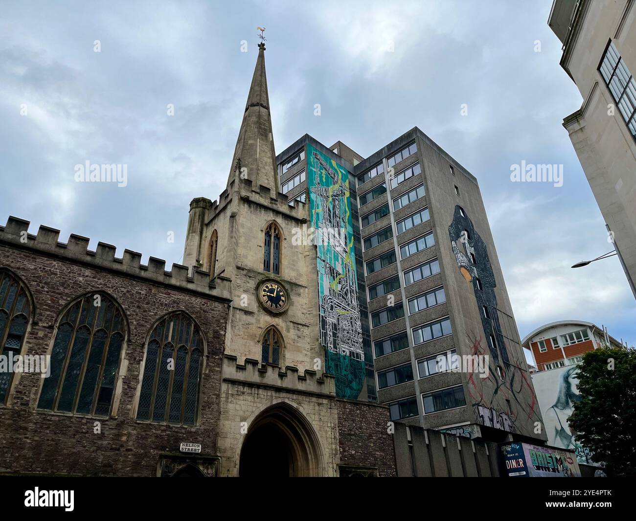 Contrast between St John The Baptist Church and a 1960s Tower Block with street art. Bristol, England, United Kingdom. 29th October 2024. - Smartphone Captured Stock Image
