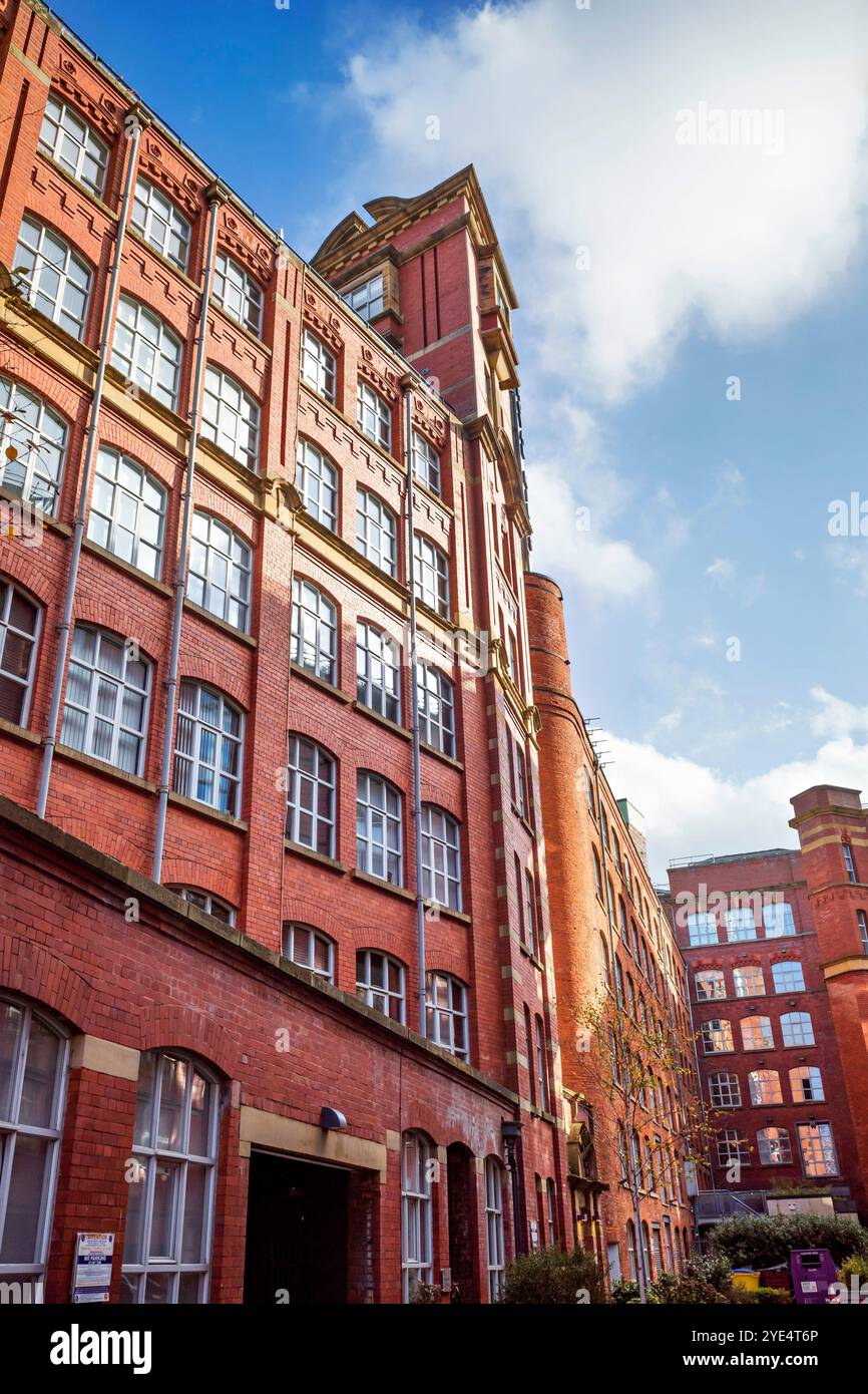 Historic red brick mill building with tall windows under a clear blue sky. Manchester city center. Stock Photo