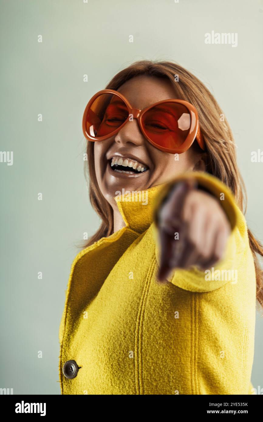 Stylish woman in her forties, wearing yellow coat and orange sunglasses ...