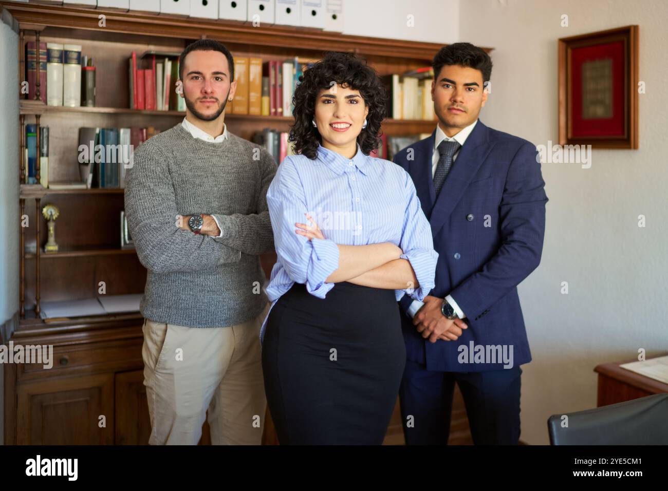Three people posing for a photo in a room with a lot of books. The ...