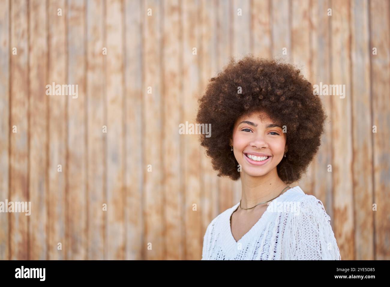 portrait of a young latina woman with afro hair smiling looking at the ...