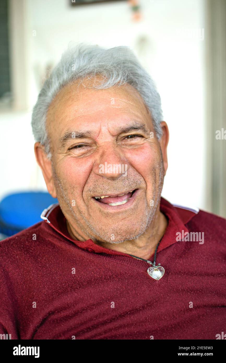 Grandfather with gray hair and red jersey smiling while looking at camera Stock Photo