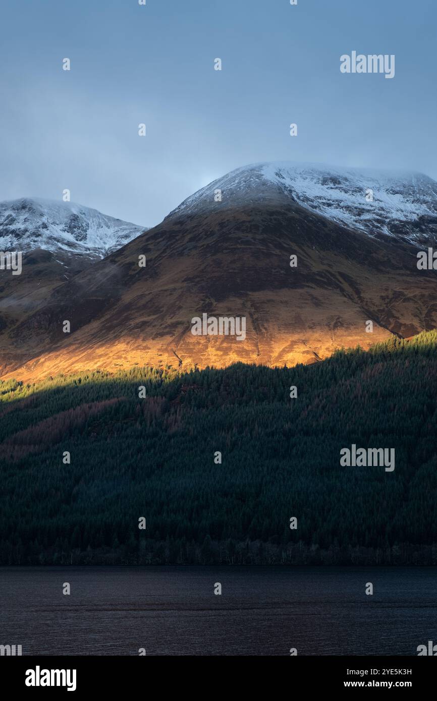Golden sunlight breaks over the rugged Scottish Highlands, illuminating ...