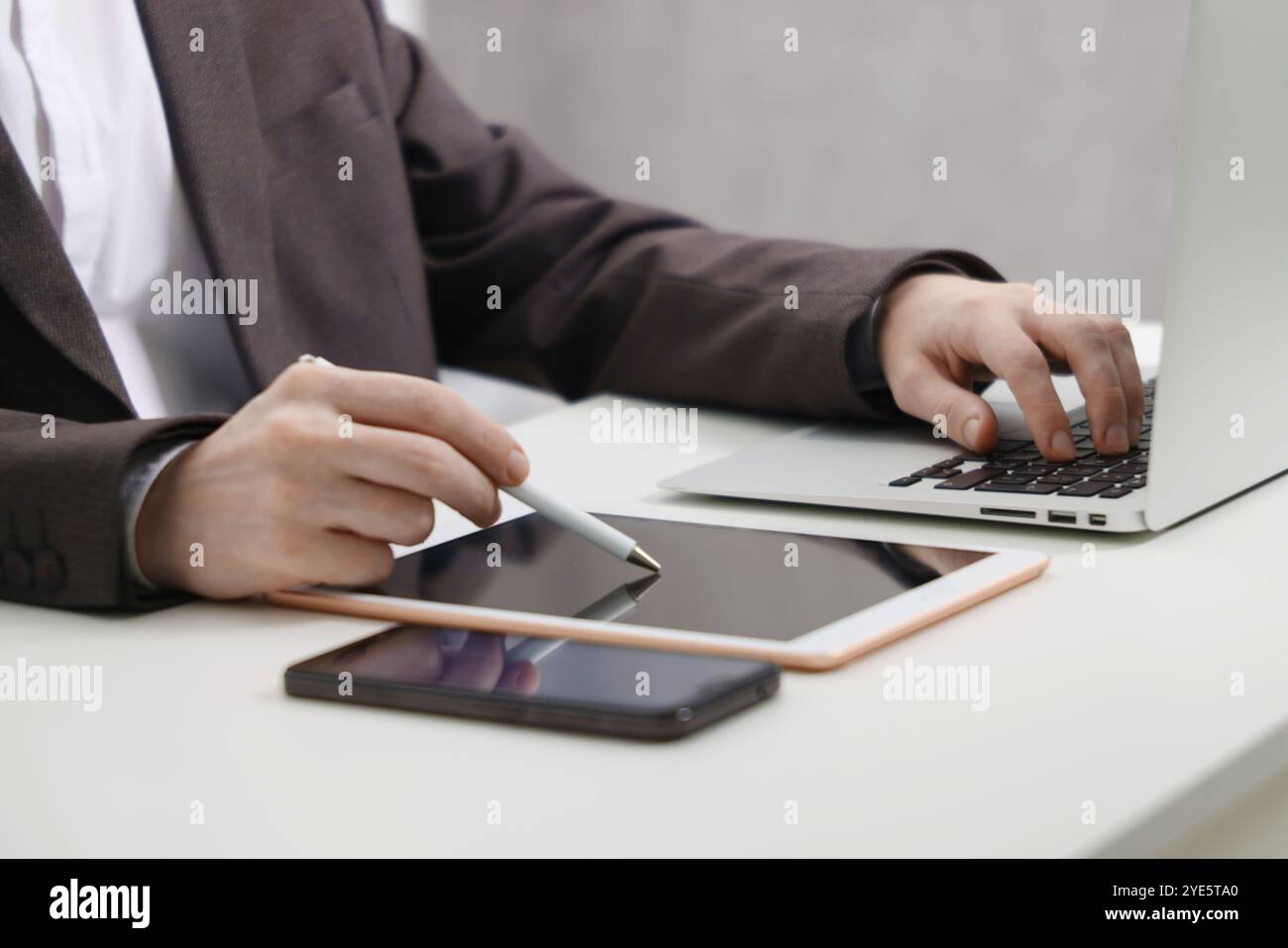 Businessman using different devices at white table indoors, closeup. Modern technology Stock Photo