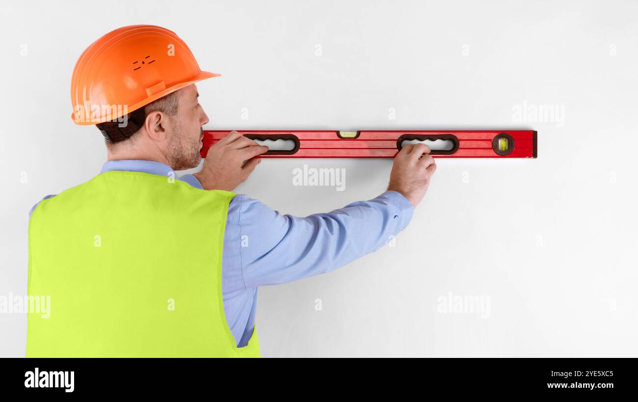 Housebuilder Using Building Level Standing Back To Camera, White Background Stock Photo