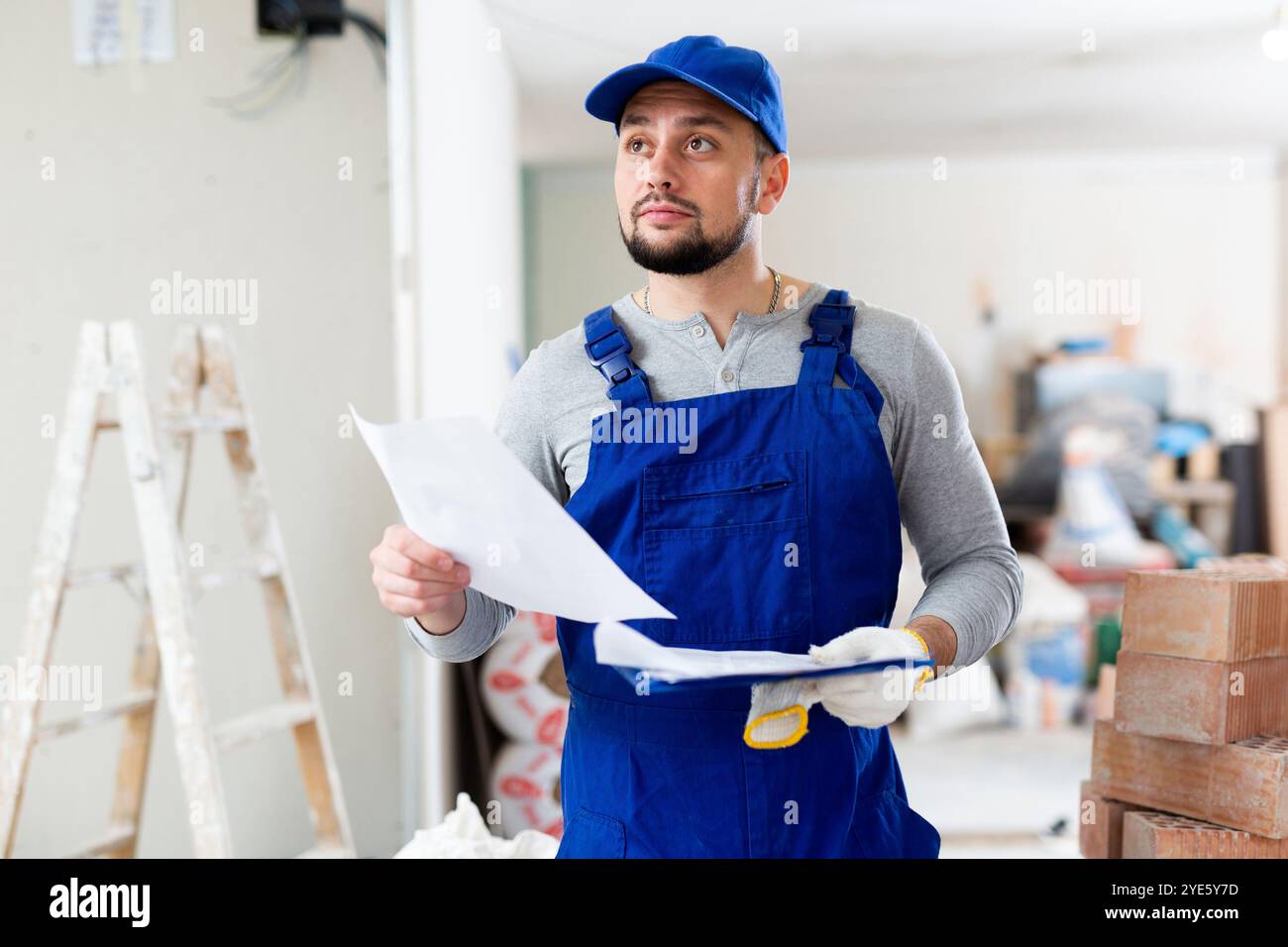 Foreman reading papers on indoor construction site Stock Photo