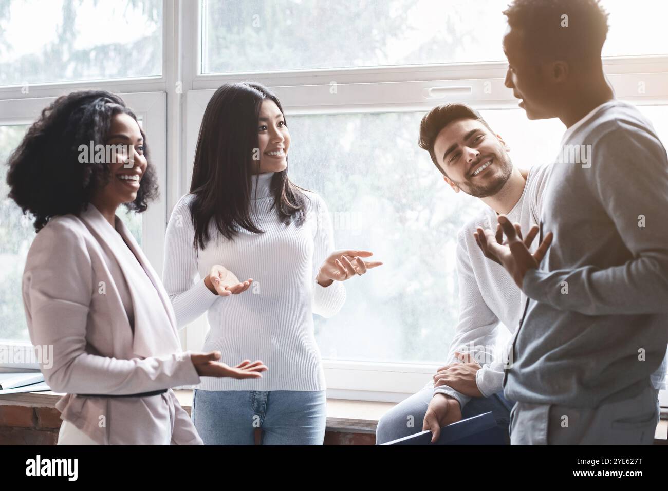 Cheerful multiracial colleagues having small talk in office Stock Photo