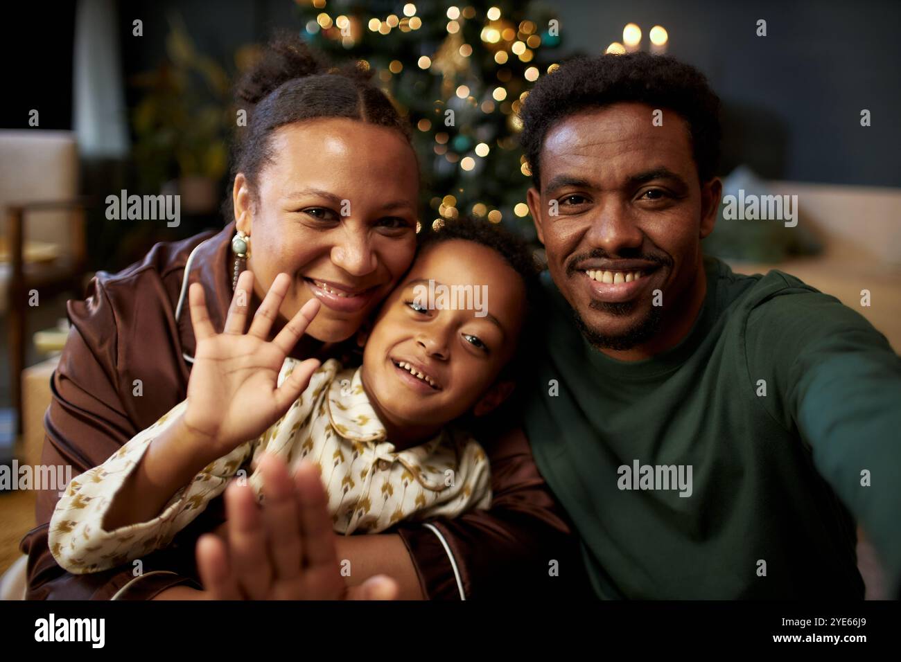 Front view portrait of happy Black family with little boy waving at ...