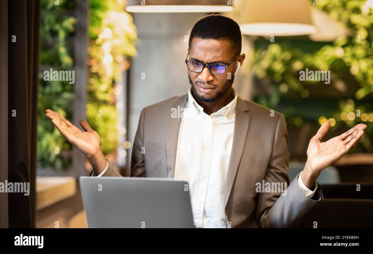 Surprised young afro manager looking at his computer Stock Photo