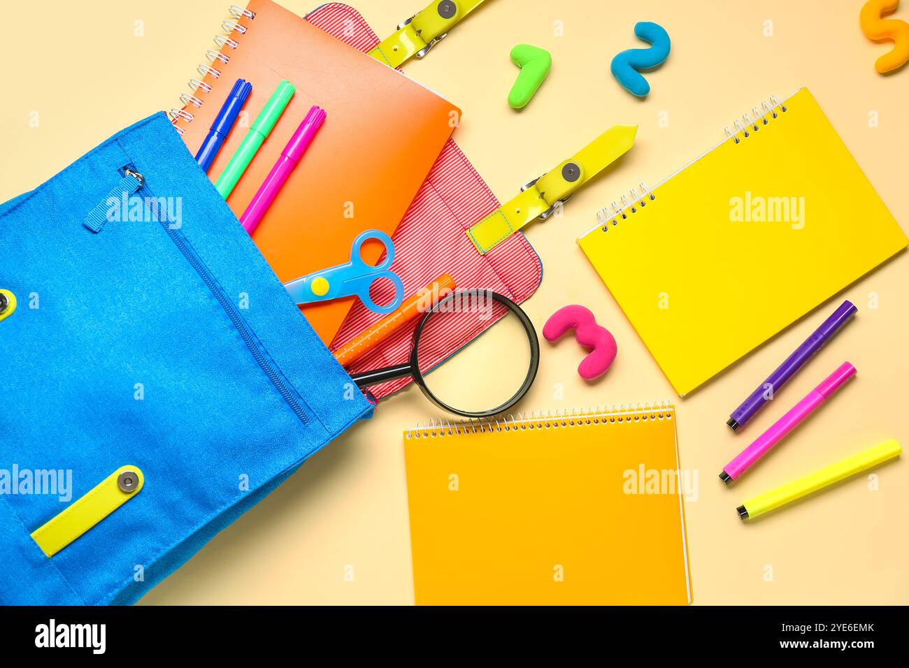 School backpack with different stationery on pale yellow background Stock Photo