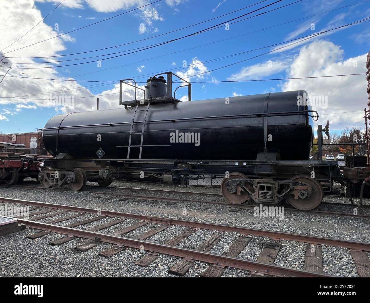 A large, black tank car sits on a set of train tracks - Smartphone Captured Stock Image