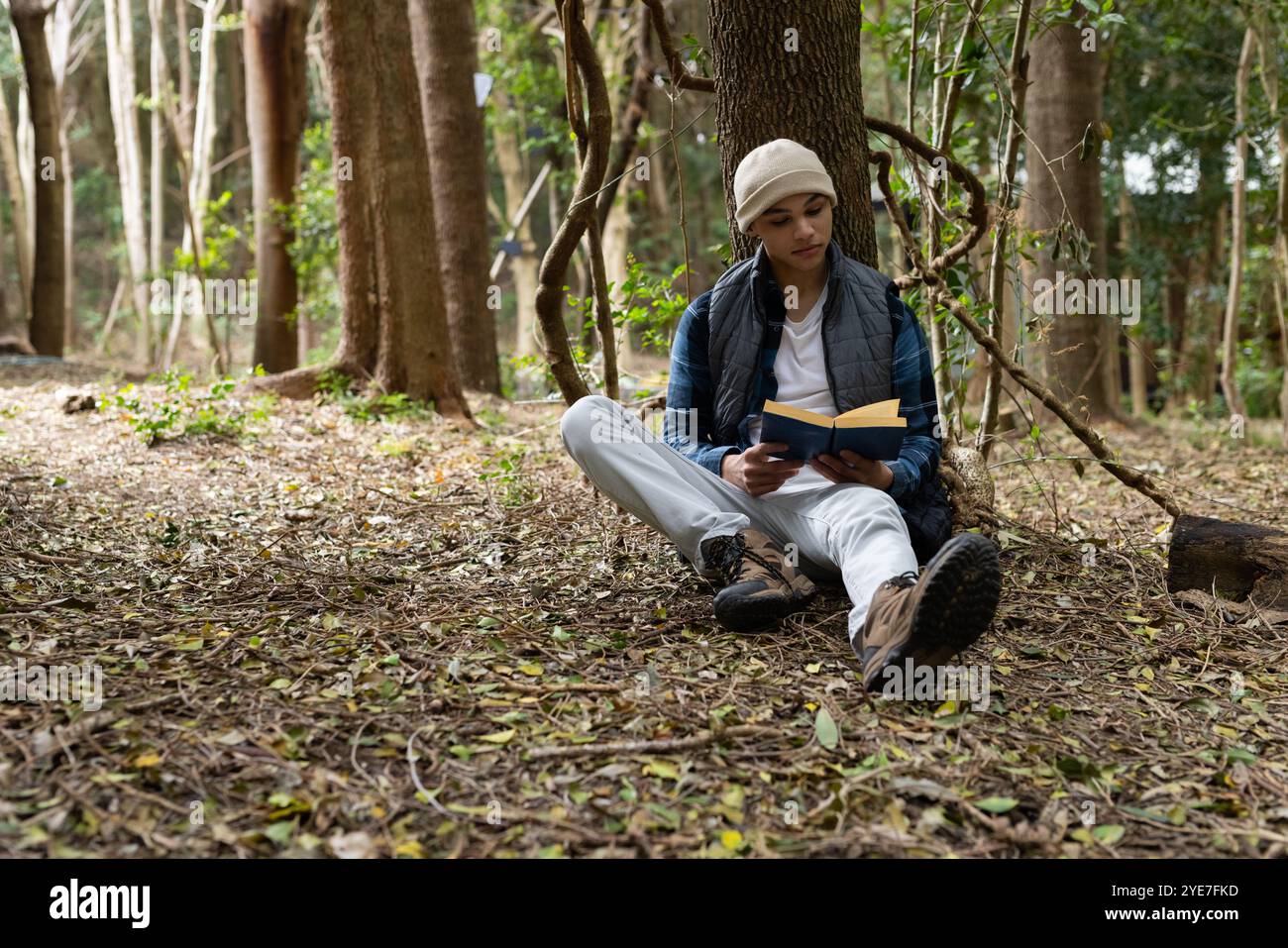 Young man reading book while relaxing in peaceful forest setting Stock Photo