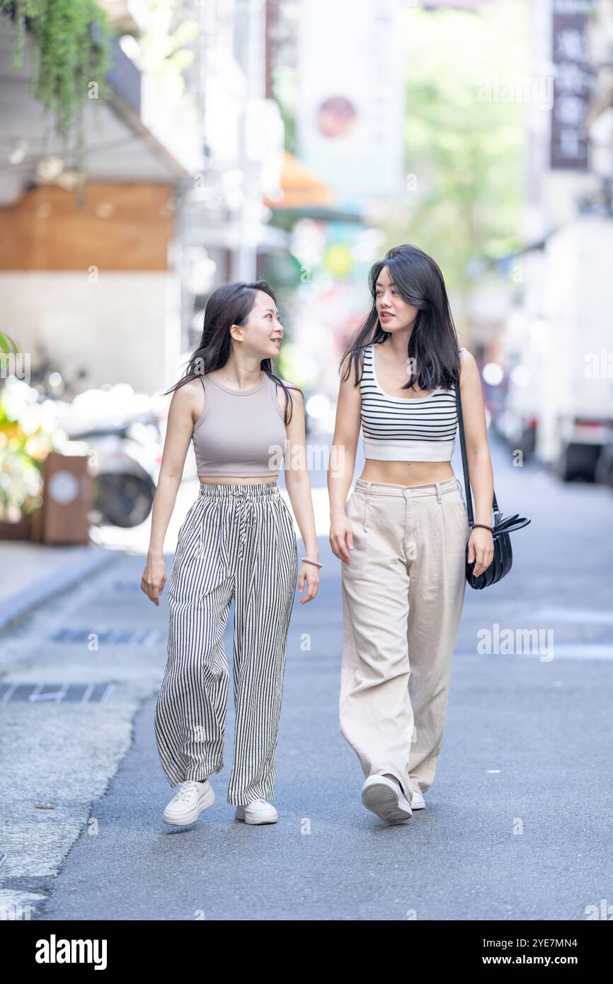 Two Taiwanese women in their 30s wearing casual outfits walk along ...