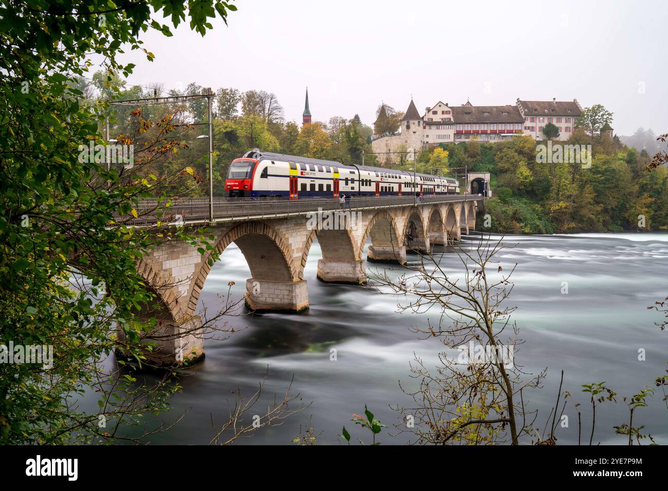 Neuhausen Am Rheinfall, Schaffhausen, SWITZERLAND. 30th Oct, 2024. PHOTO-COMPOSITION (long and short exposure mixture): Train passing over the RheinbrÃ¼cke bei Laufen bridge at the beautiful Swiss Rhine Falls, seen during the fall time. (Credit Image: © Andreas Stroh/ZUMA Press Wire) EDITORIAL USAGE ONLY! Not for Commercial USAGE! Stock Photo