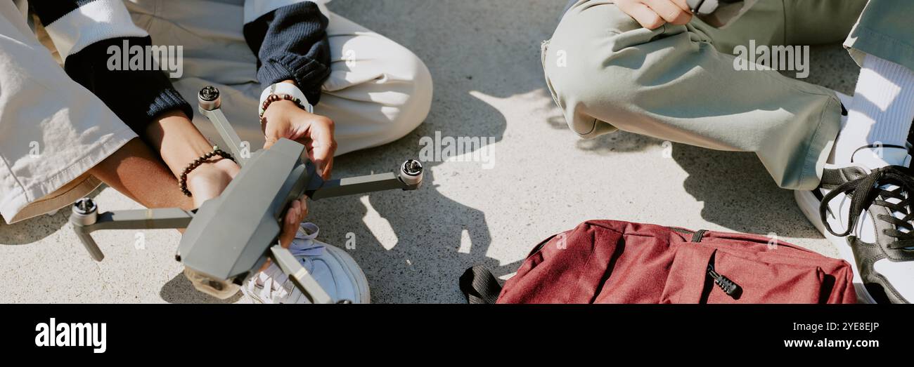 Website banner with two unrecognizable boy repairing black drone together outside Stock Photo