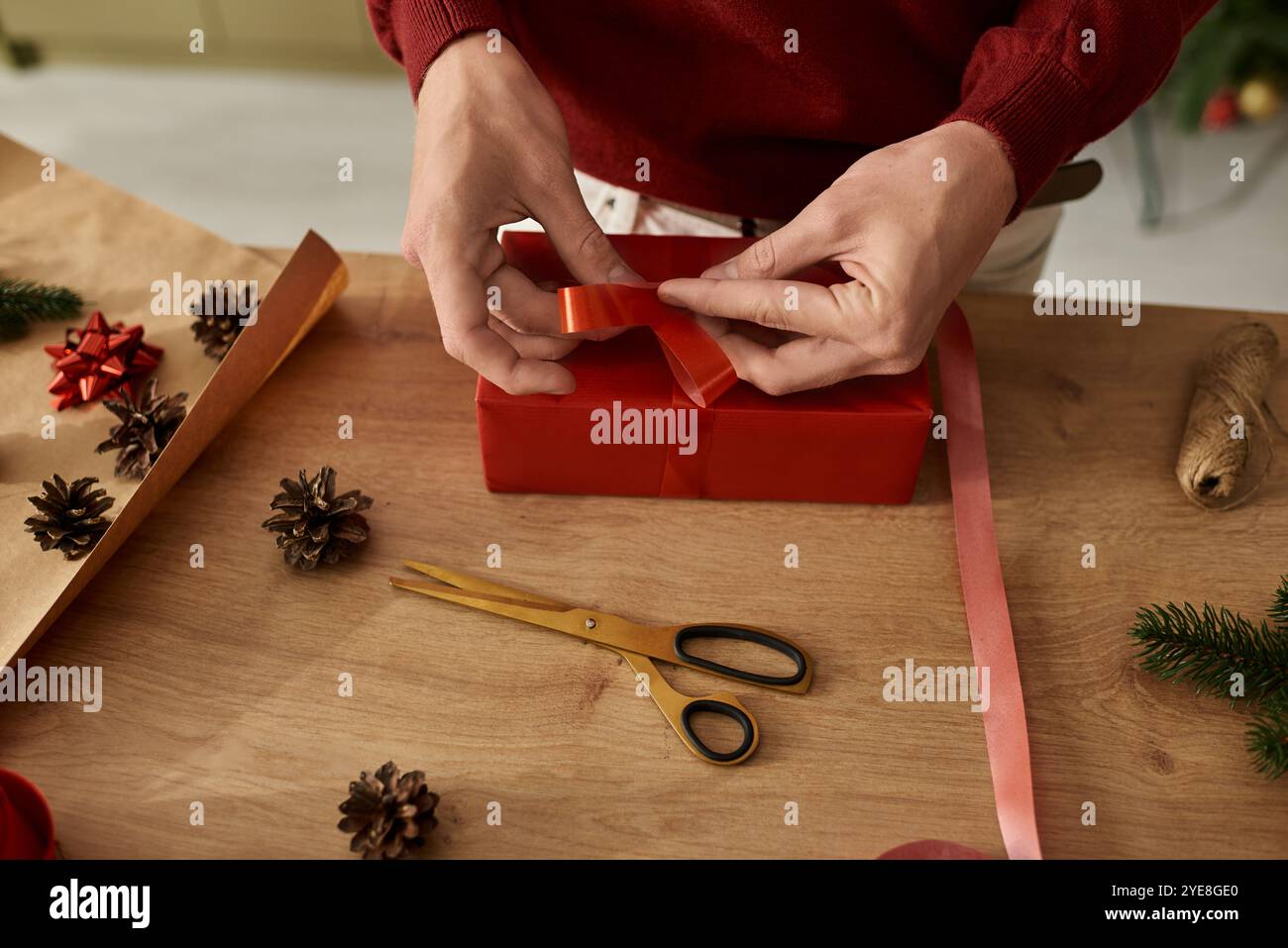 A young man is tying a beautiful ribbon around a thoughtfully wrapped ...