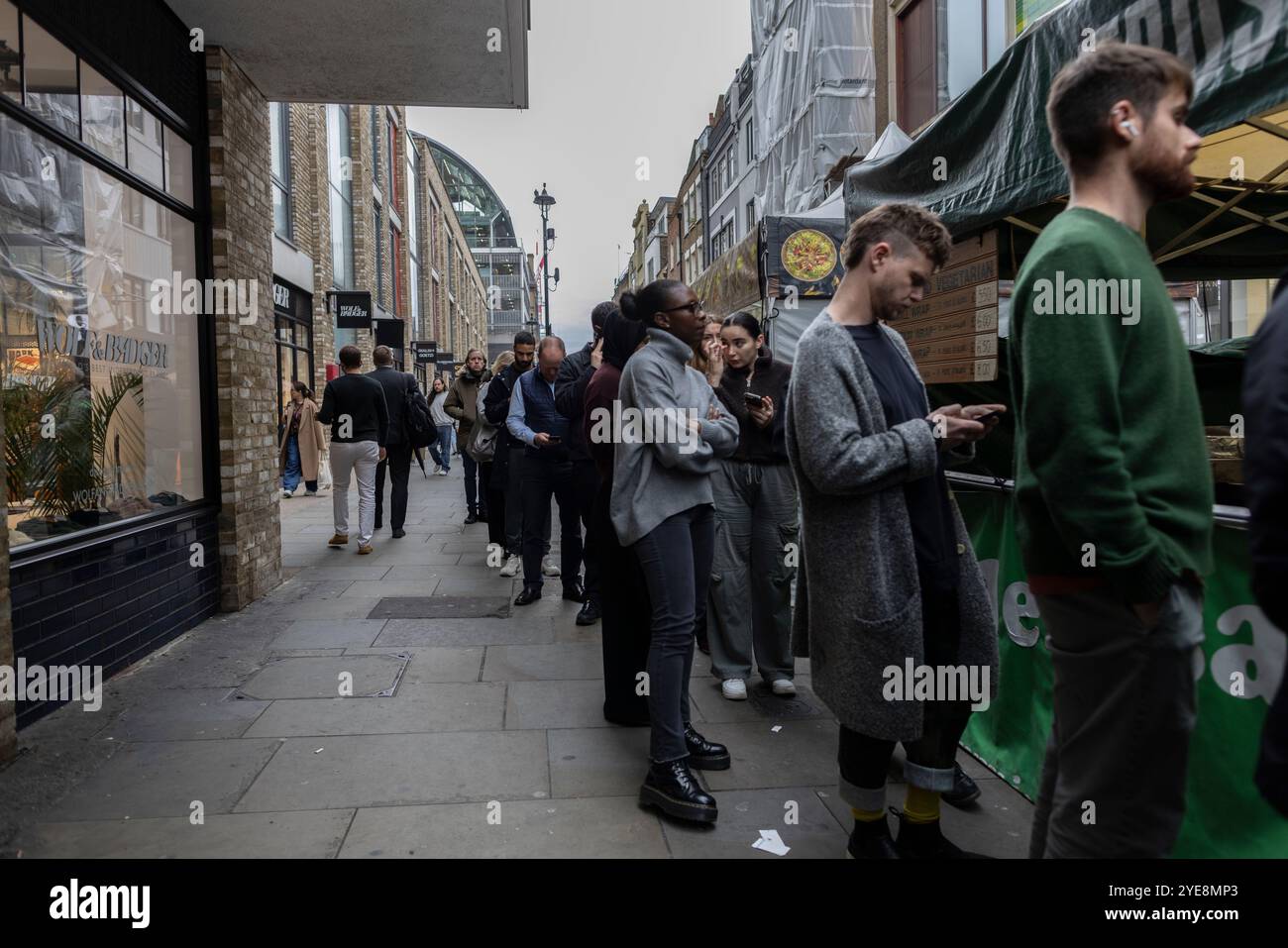 Berwick Street Market, people queue at stalls for take-away food at the historic market during a working week lunchtime, Soho, London, England, UK Stock Photo