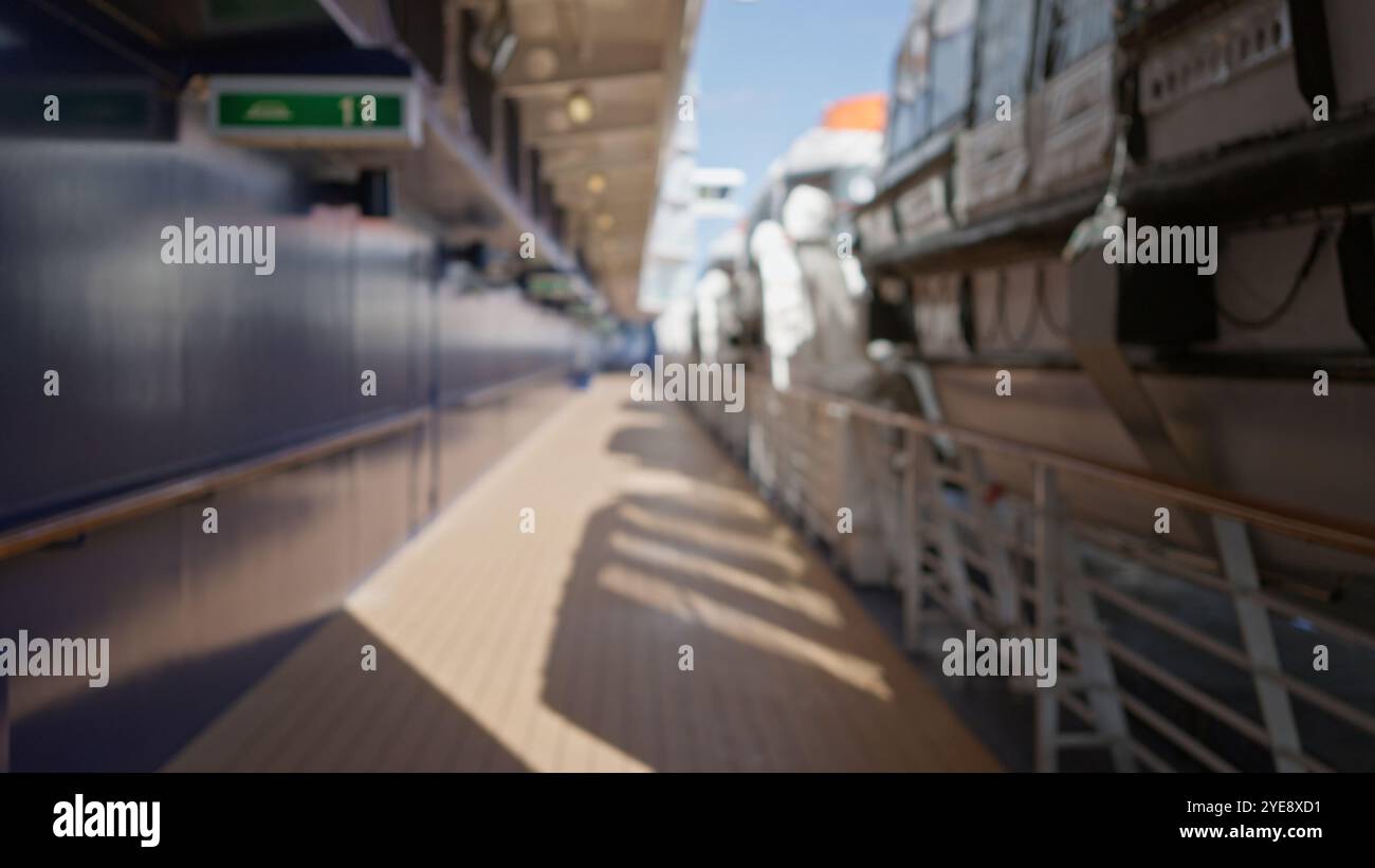 Blurred view of a cruise ship deck with lifeboats along the railing in bright sunlight, emphasizing the depth and nautical environment during travel. Stock Photo