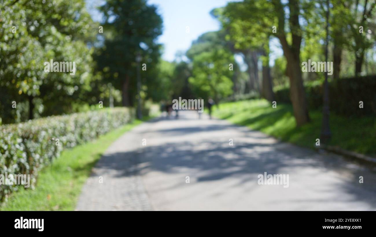 Blurred view of people walking in villa borghese gardens, surrounded by ...