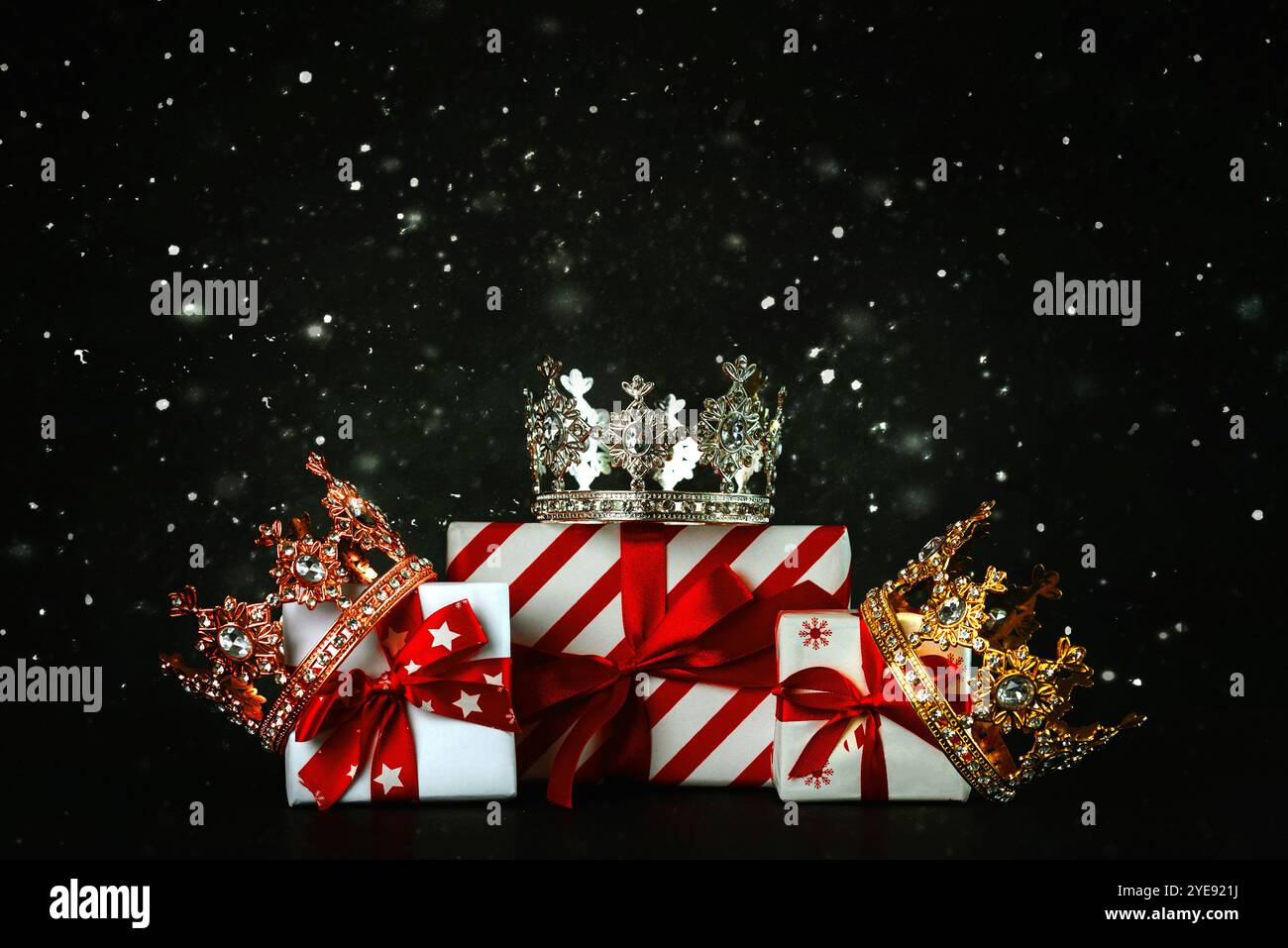 Crowns of the three wise men with Christmas gift boxes and snowflakes on a dark background. Concept for Dia de Reyes Magos day. Three Wise Men Stock Photo