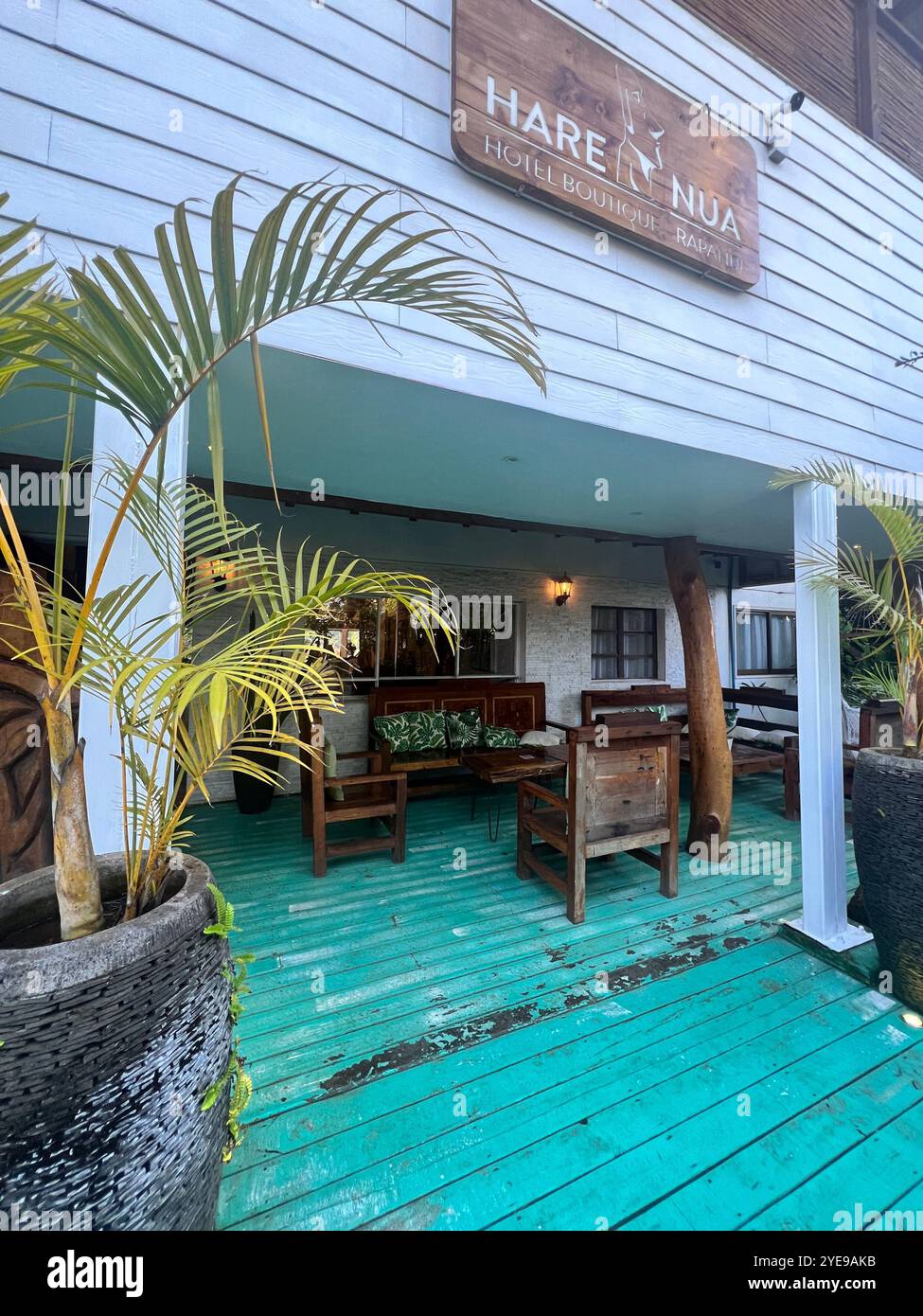 Charming entrance of Hare Nua Boutique Hotel on Easter Island Chile Rapa Nui featuring rustic wood decor, tropical plants and inviting outdoor seating - Smartphone Captured Stock Image
