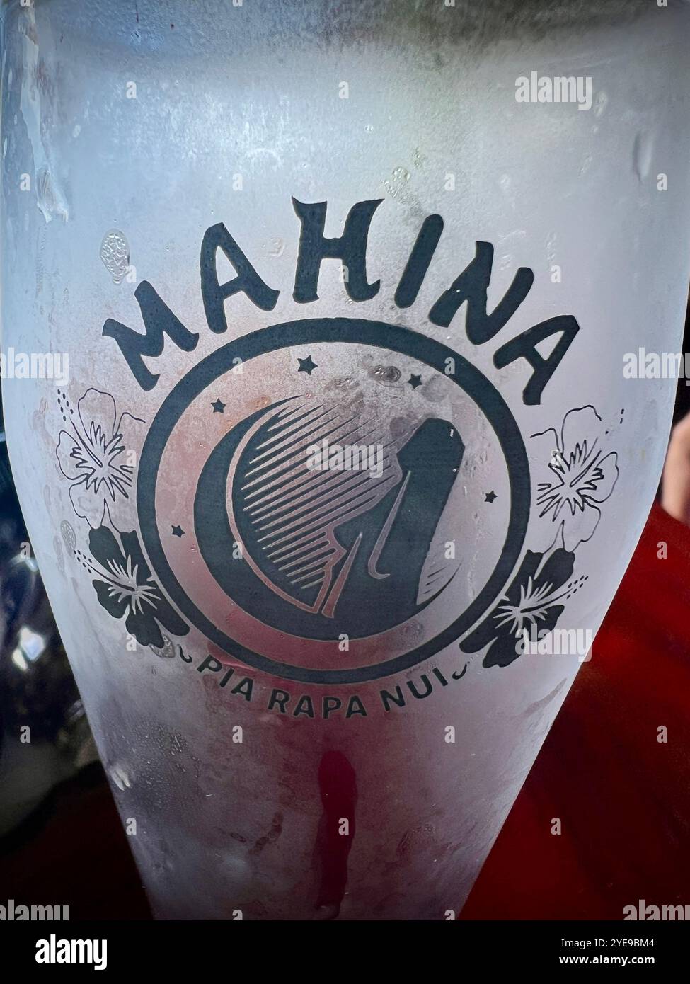 Frosted glass with Mahina Pia Rapa Nui logo, featuring iconic Easter Island Moai design and hibiscus flowers, representing Polynesian culture - Smartphone Captured Stock Image