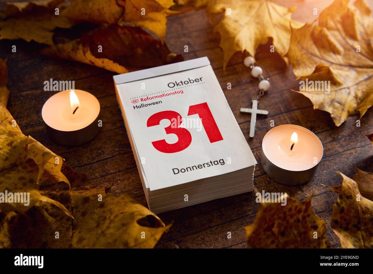 Bavaria, Germany - October 30, 2024: Calendar with date October 31. Reformation Day holiday and Halloween in one day, surrounded by fall leaves and candlelight *** Kalender mit Datum 31 Oktober. Reformationstag Feiertag und Halloween an einem Tag, umgeben von Herbstblättern und Kerzenlicht Stock Photo