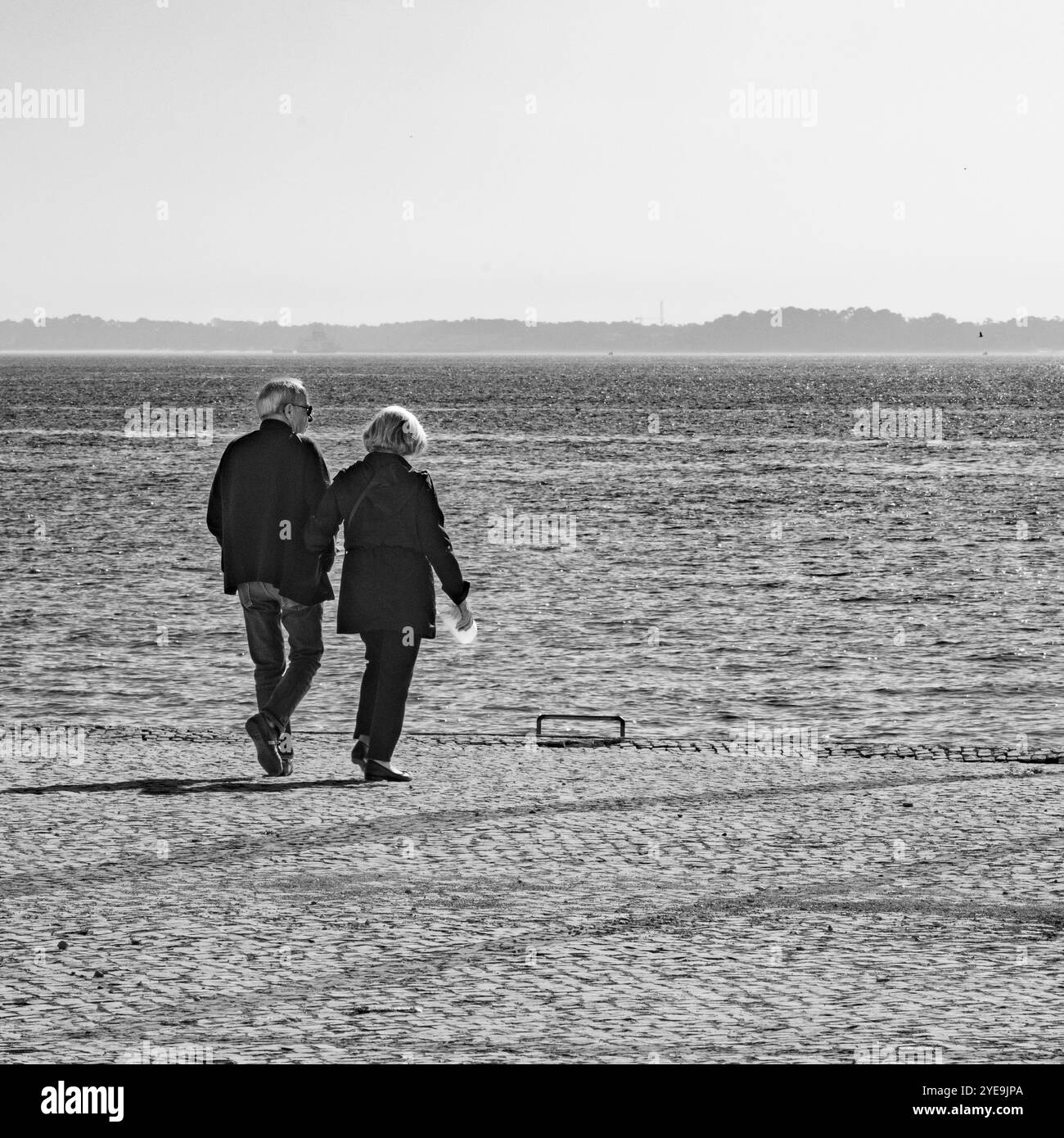 Senior couple walks on a promenade in the port city of Setubal, Portugal on a sunny day; Setubal, Portugal Stock Photo