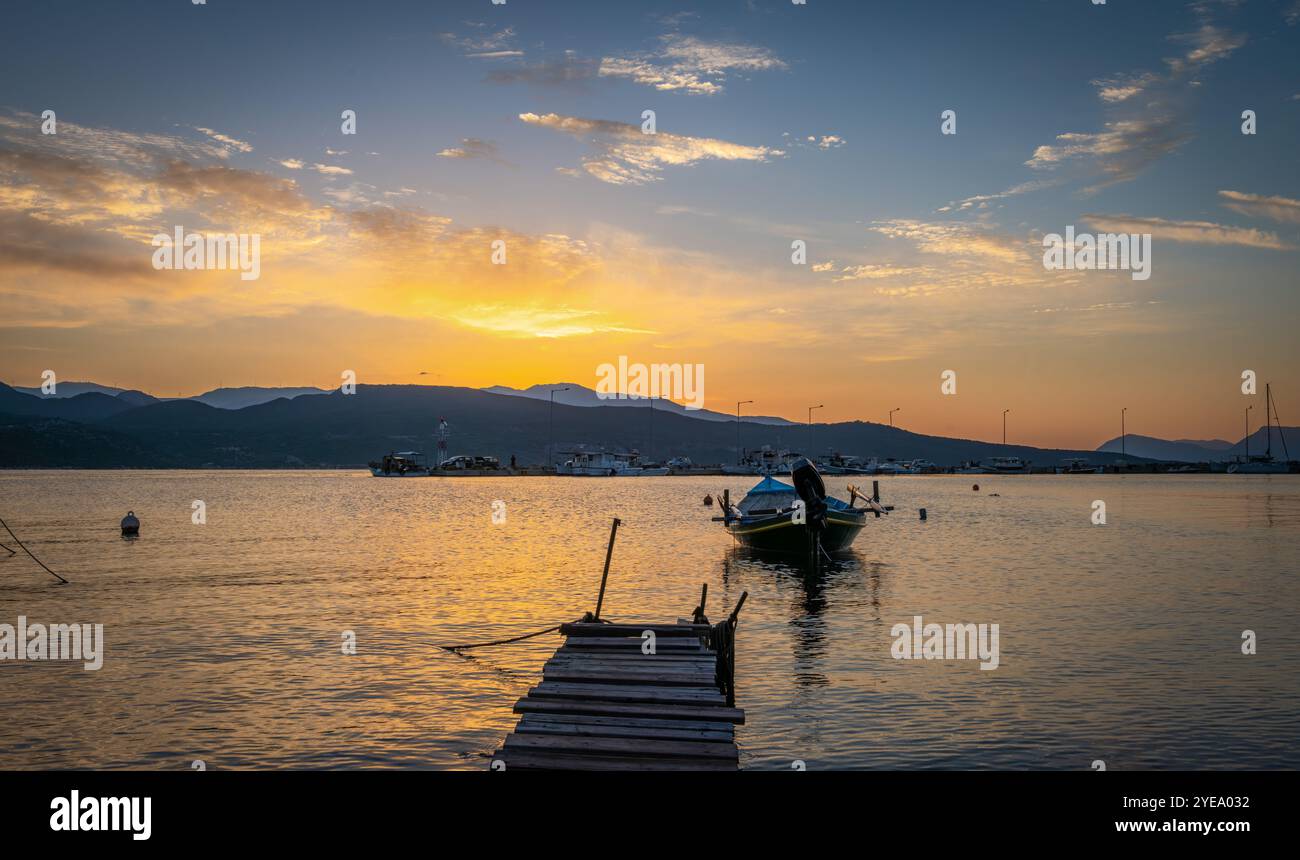 Small boats moored in a harbour on a morning with a beautiful golden sunrise and sky clouds. Stock Photo