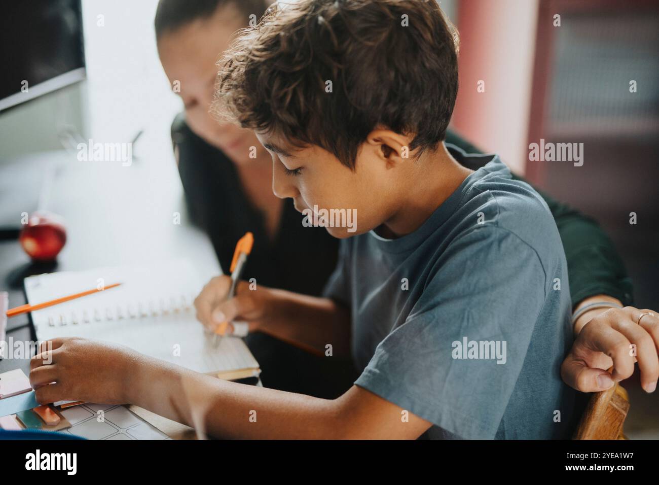 Mother helping son doing homework while sitting at home Stock Photo