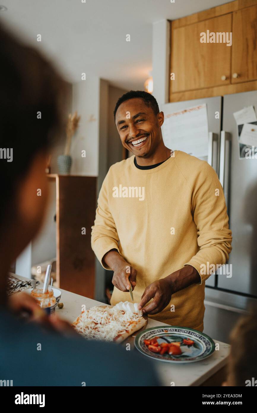 Happy mature man making pizza while standing in kitchen at home Stock Photo