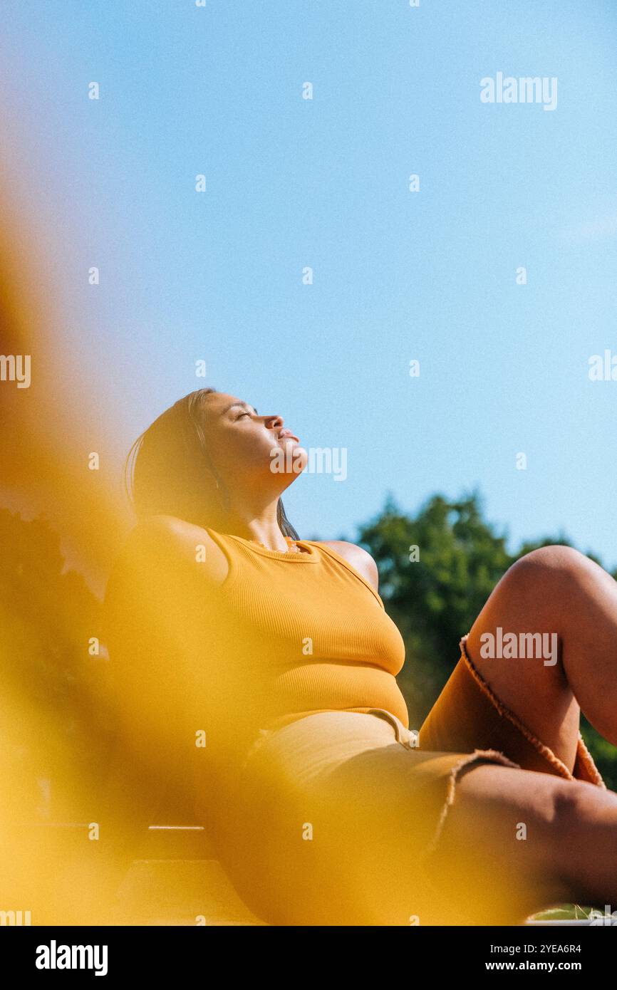 Young woman with eyes closed posing under blue sky Stock Photo