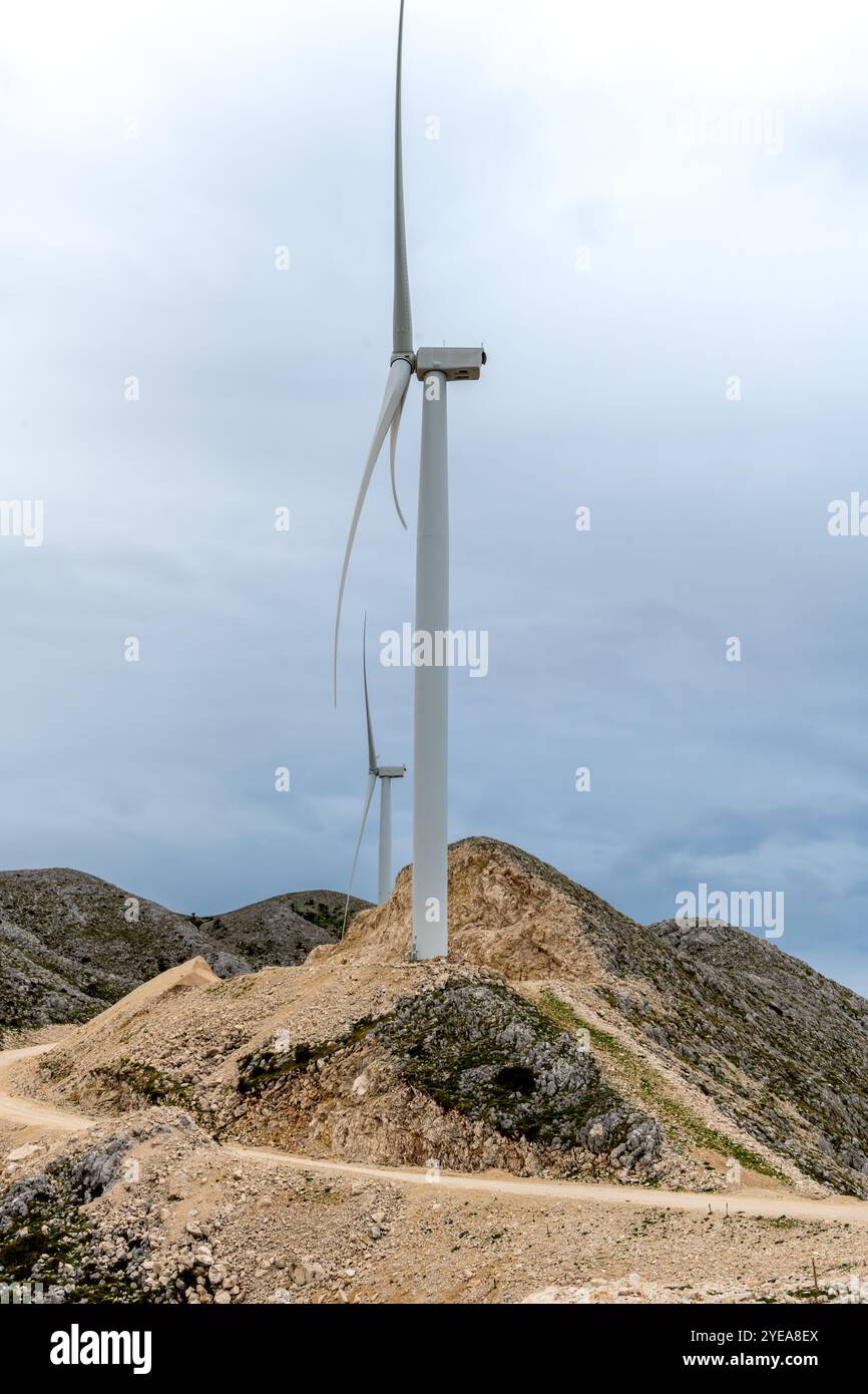 A mountain top wind farm with wind turbines on a cloudy day. Stock Photo