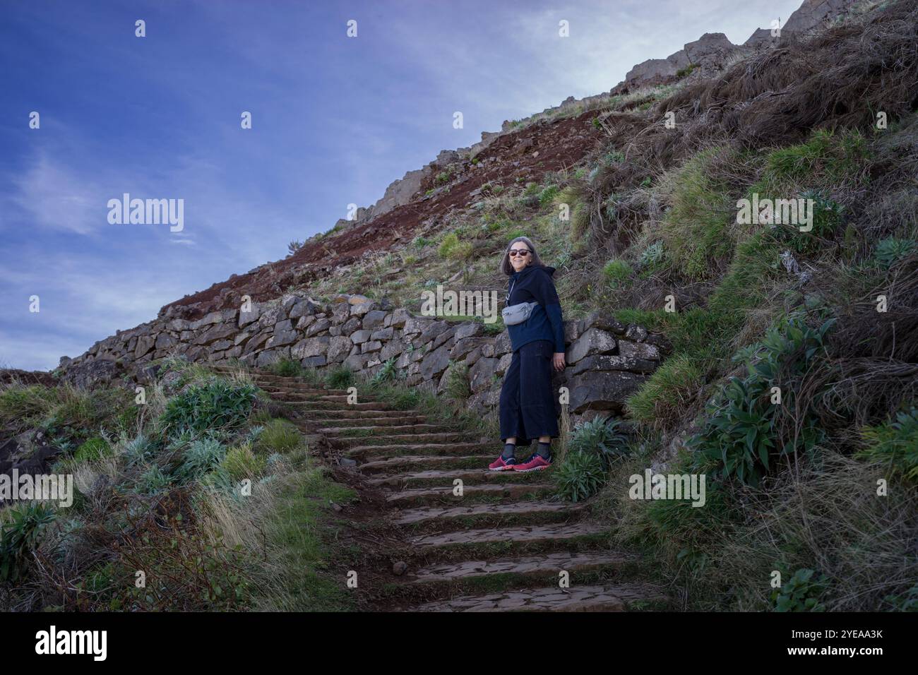 Female tourist stands posing on the steps at the hiking destination ...