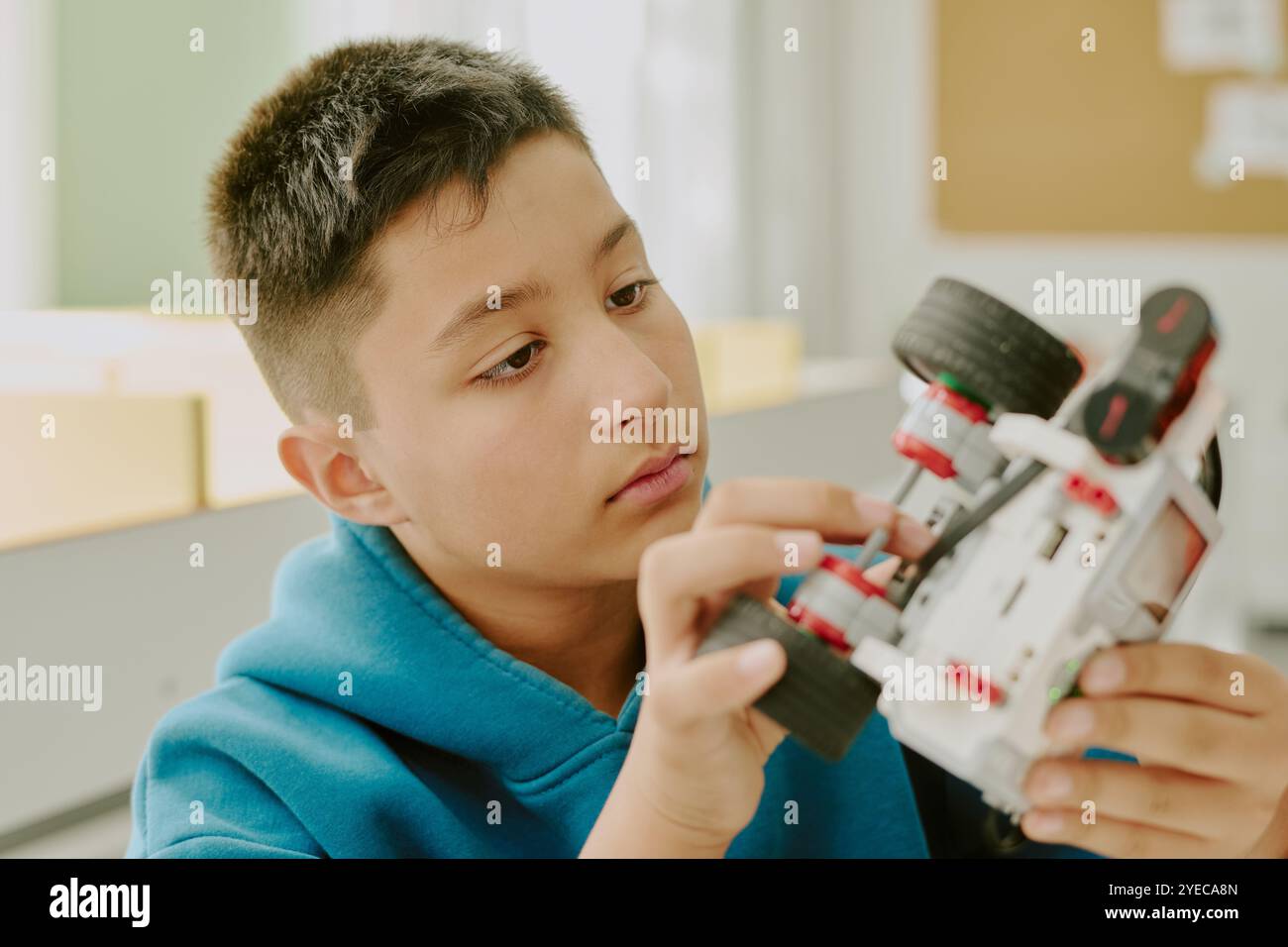 Medium close up of curious boy testing robot while checking its ...