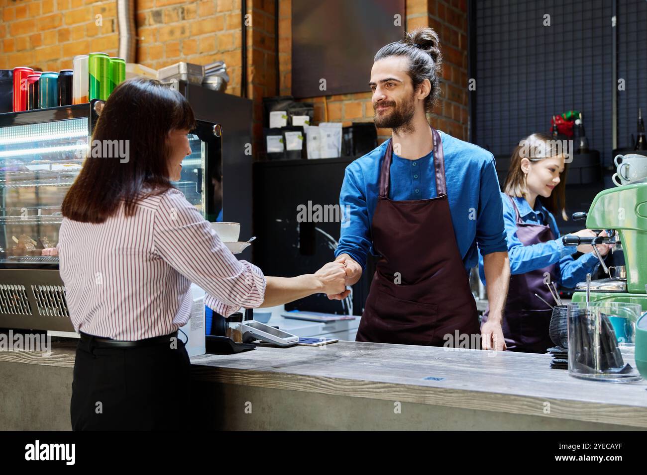 Guy working in cafe with cup of coffee at bar counter serving female ...