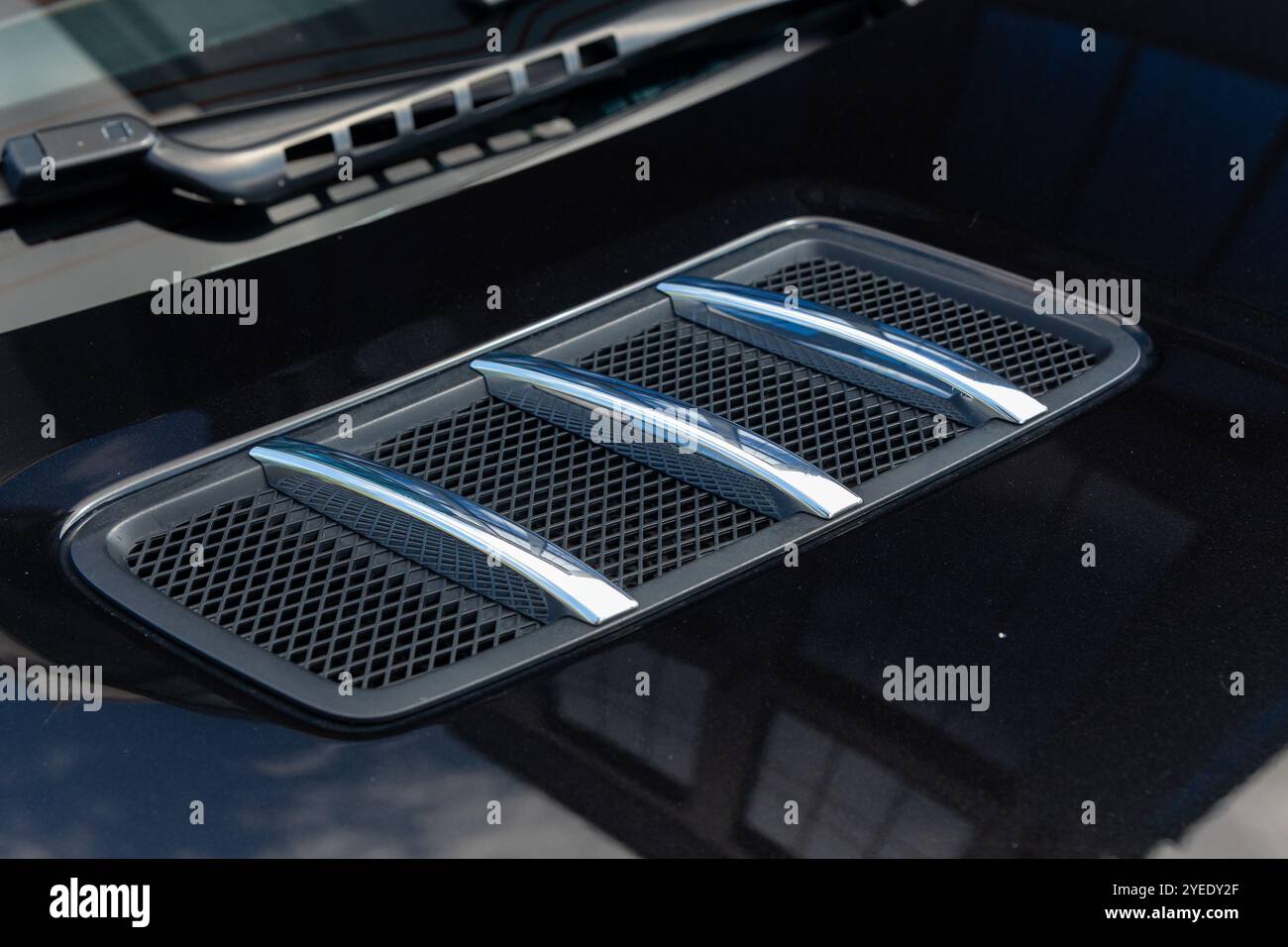 Close-up of chrome-plated air intakes on the hood of a black car ...