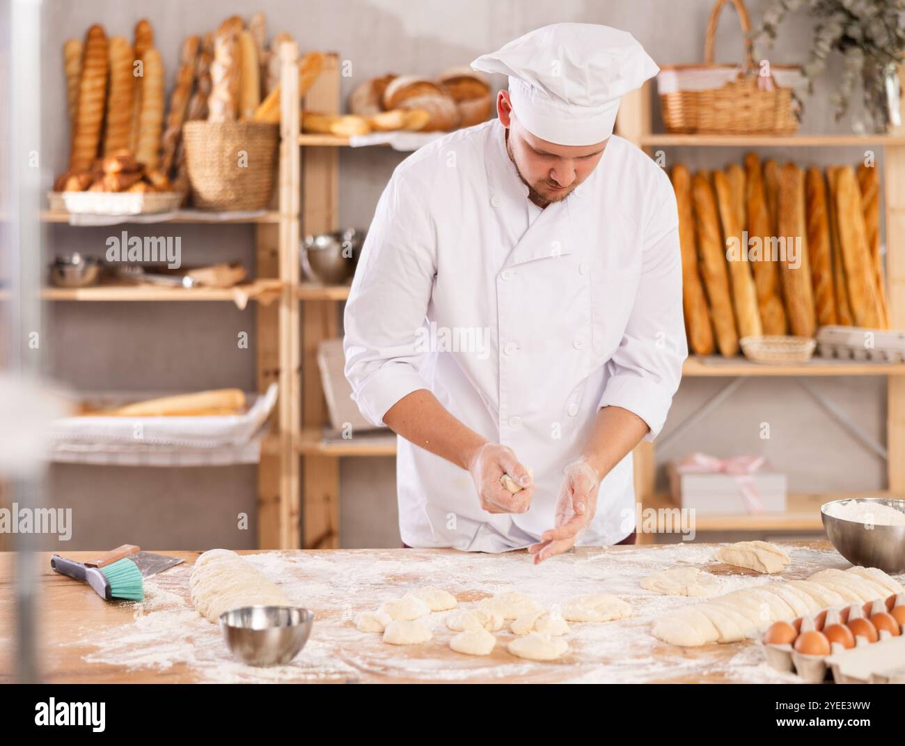 Guy works as baker in bakery, molds pies from dough, creates croissants ...