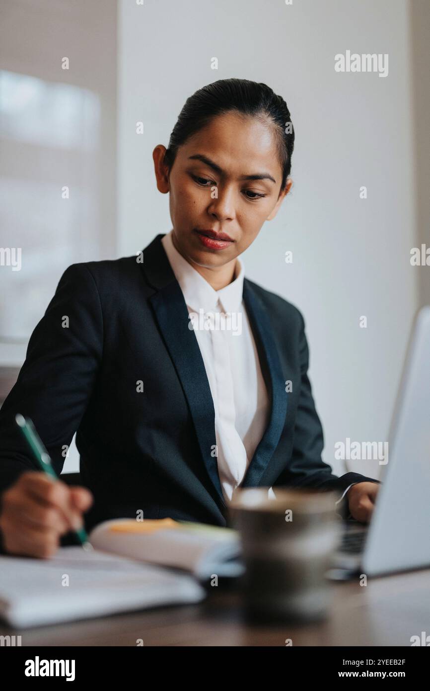 Businesswoman writing in diary while working in office Stock Photo