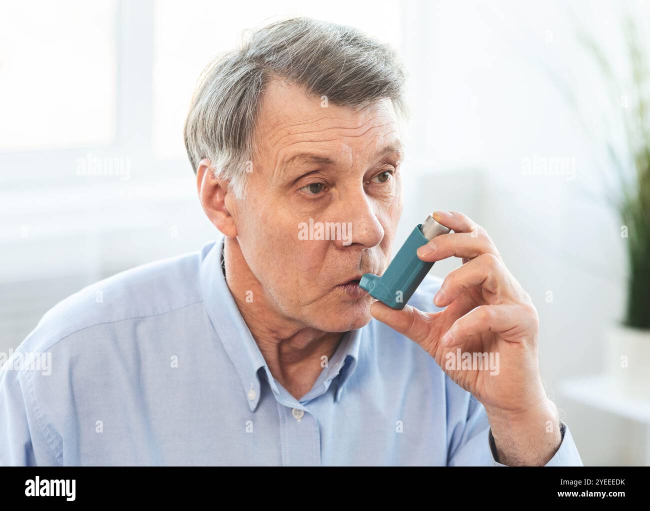Elderly man using asthma inhaler for allergies Stock Photo