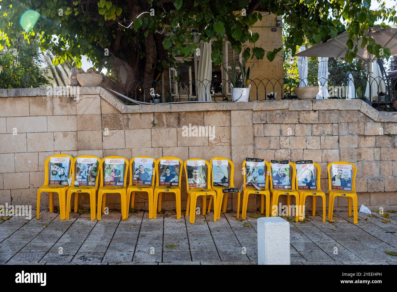 Zikhron Ya'akov, Israel - October 20, 2024, yellow chairs with photographs of Israeli hostages taken by Hamas terrorists on October 7. Stock Photo