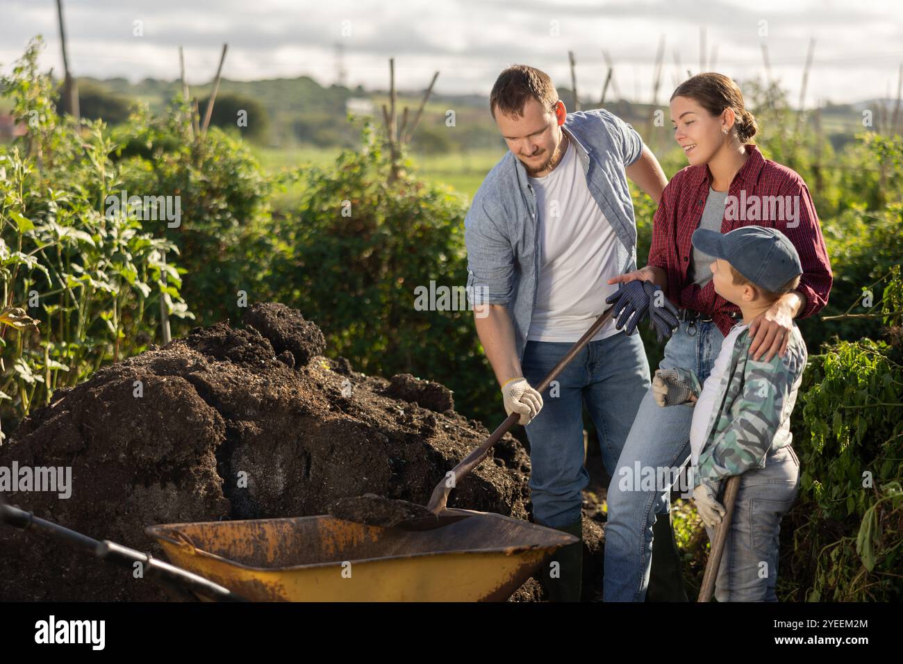 Man woman and boy putting soil in wheelbarrow Stock Photo - Alamy