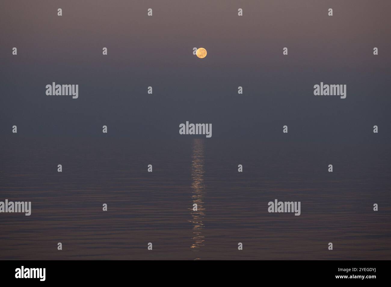 Super moon setting over a calm ocean during sunrise in the Timor Sea Stock Photo