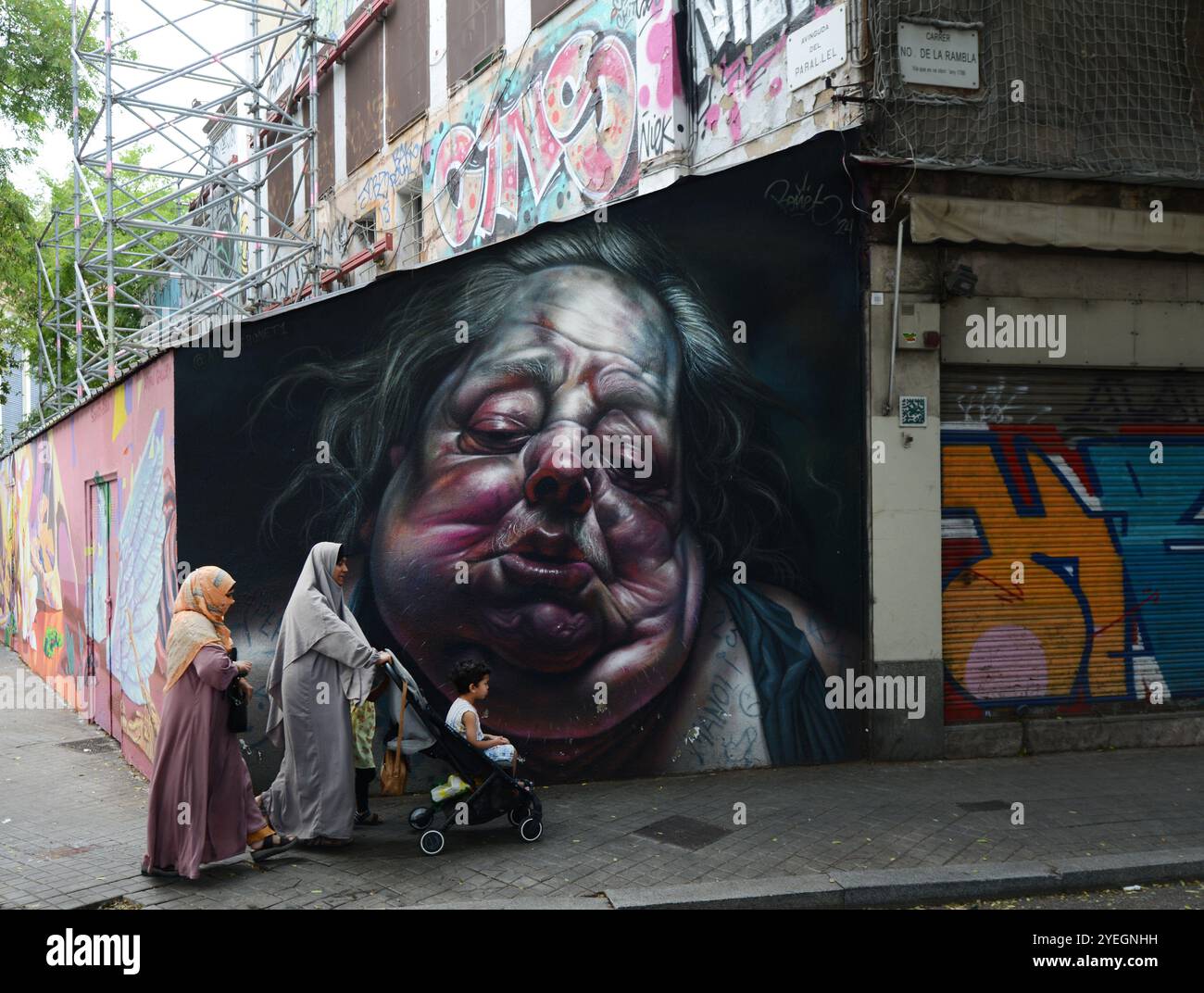 Muslim women walking by a beautiful wall mural on the Graffiti wall on Carrer Nou de la Rambla in Barcelona, Spain. Stock Photo