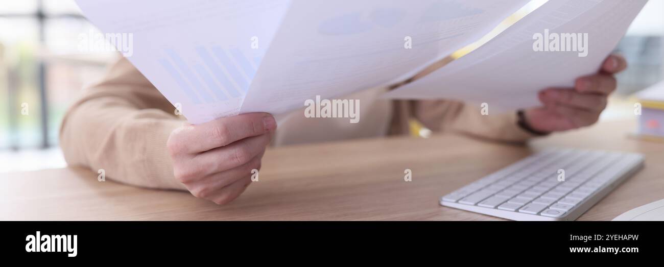 Serious grey haired woman studies reports sitting at table Stock Photo
