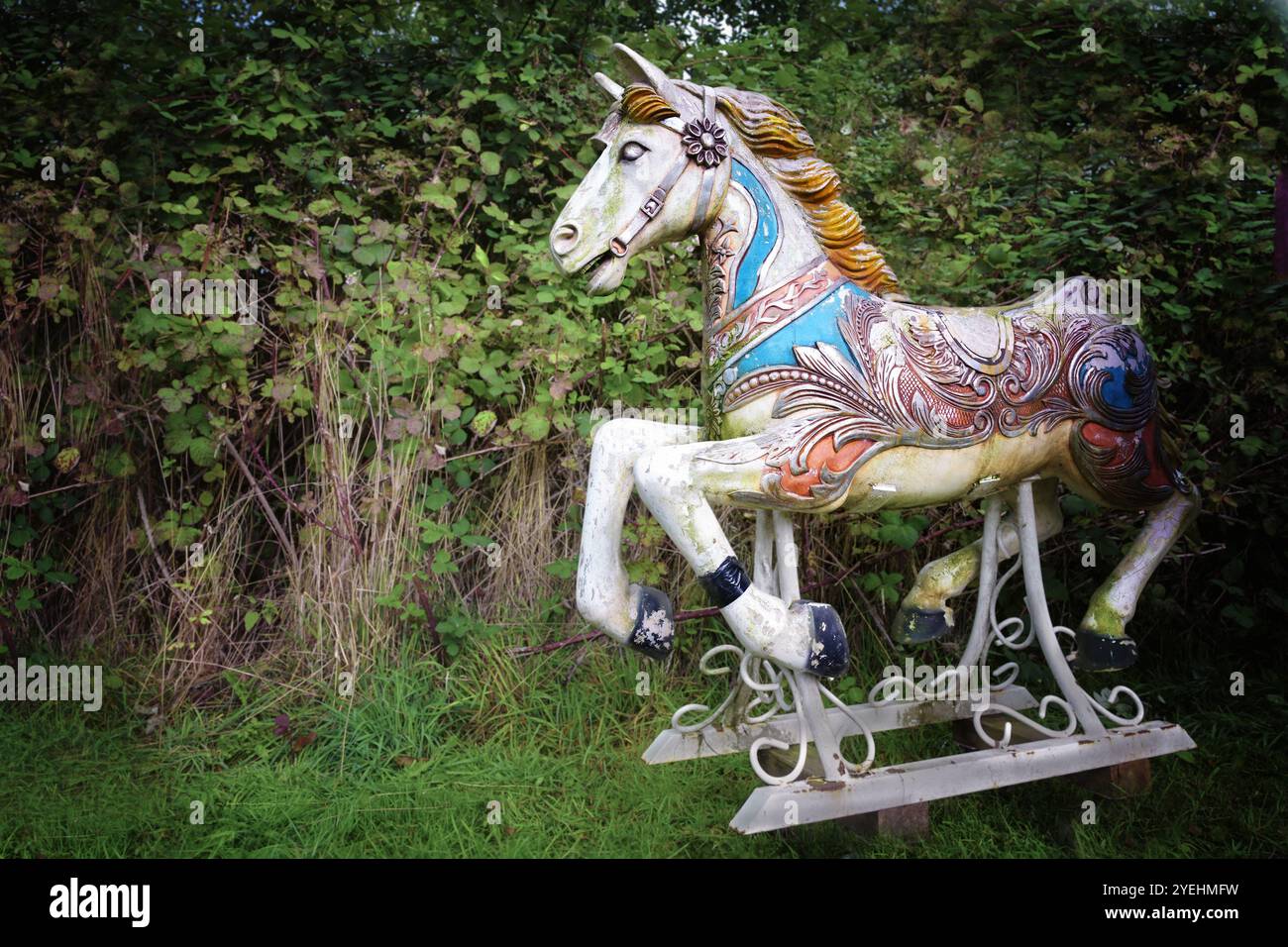 Old wooden horse of a nostalgic merry go round standing in a backyard, weathered and partly covered with moss but still beautiful, copy space, selecte Stock Photo