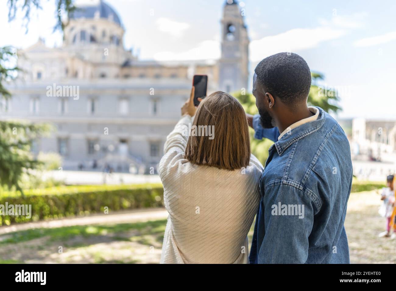 Rear view of a multi-ethnic couple taking a photo of a monument visiting a city Stock Photo