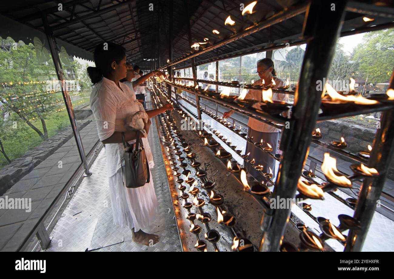 Sri Lankan pilgrims pour oil into candle holders at the Buddhist Temple of the Tooth or Sri Dalada Maligawa, Kandy, Central Province, Sri Lanka, Asia Stock Photo